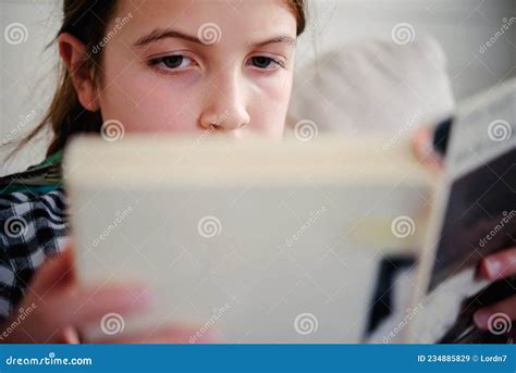 Schoolgirl Reading A Book At Home In A Living Room Reading Assignment