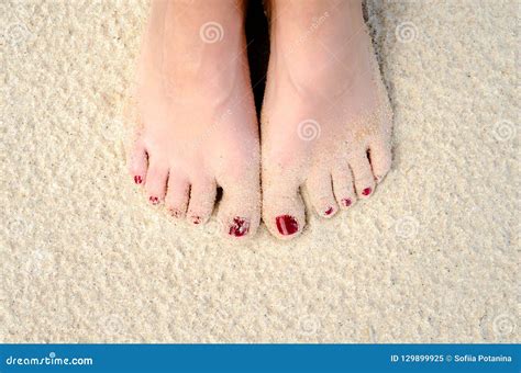 Female Legs With A Red Pedicure On The Sand On The Beach Closeup Stock