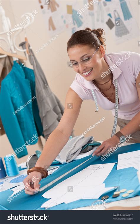 Female Fashion Designer Working At Studio With Pattern Cuttings And