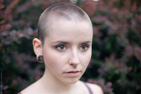 A Girl With A Shaved Head And Red Bushes In The Background By Erik Naumann