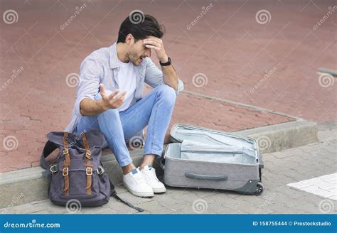 Sad Man Sitting At International Airport With Luggage Stock Photo