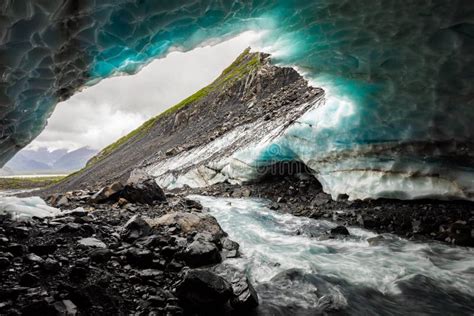 Scenic Glacier Ice Caves With River Flowing Out From Inside Stock Photo