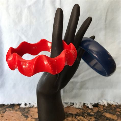 a red and black plastic ring on top of a mannequin s hand