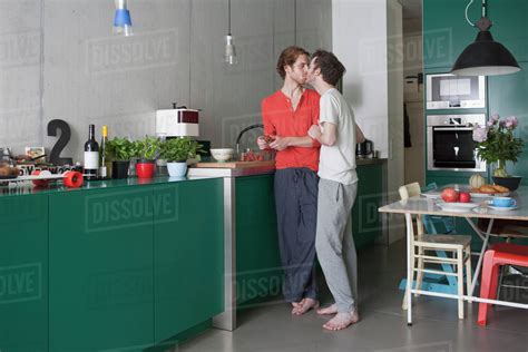 Full Length Of Romantic Gay Couple Kissing In Kitchen Stock Photo
