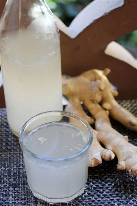 A Bottle Of Water Next To A Glass Filled With Liquid And Ginger Root On