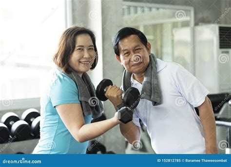 asian senior man and woman exercise lifting dumbbell in fitness gym elderly healthy lifestyle