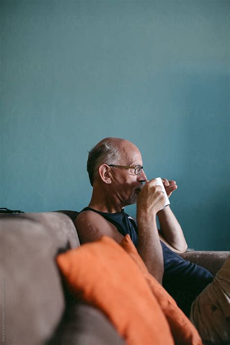 Man Sipping Coffee On Couch By Rob And Julia Campbell