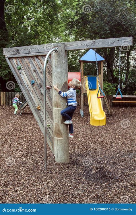 Boy Climbs A Wooden Pole With Steps To Slide Down A Fire Pole On A