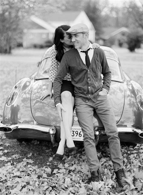 a man and woman sitting on top of an old car