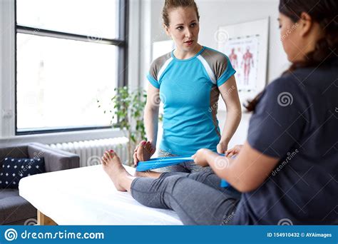 Caucasian Woman Physiotherapist Strectching The Leg And Knee Of A Mid Adult Chinese Female