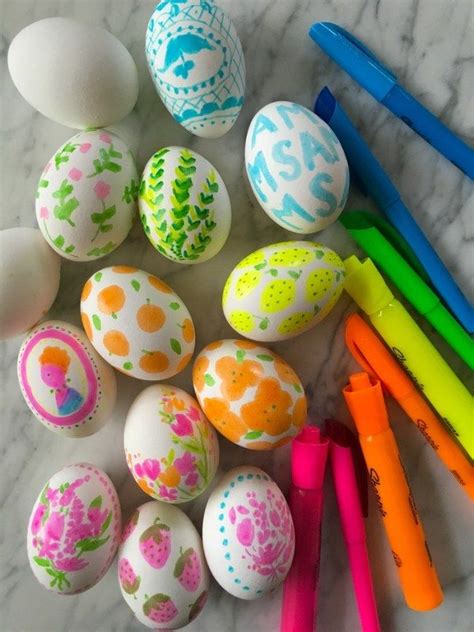 An Assortment Of Painted Eggs And Markers On A Marble Surface