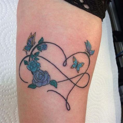 A Heart Shaped Tattoo With Blue Roses And Butterflies On The Side Of The Arm