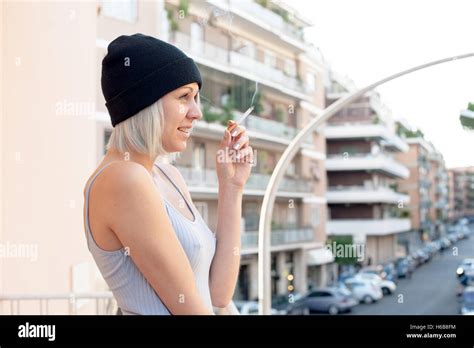 Young Teen Woman Smoking Cigarette And Smiling Outdoor With Urban Scene