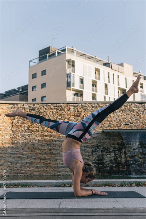 Vertical Shot Of A Young Woman Performing Yoga Outdoors On Her Mat