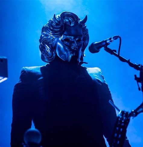 A Man With A Mask On Standing Next To A Bike In Front Of A Blue Light
