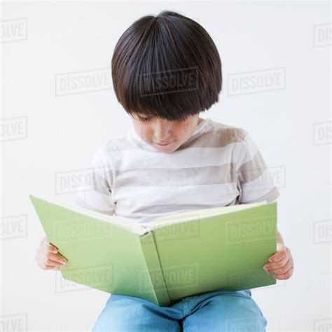 Studio Shot Of Young Boy Reading Book Stock Photo Dissolve