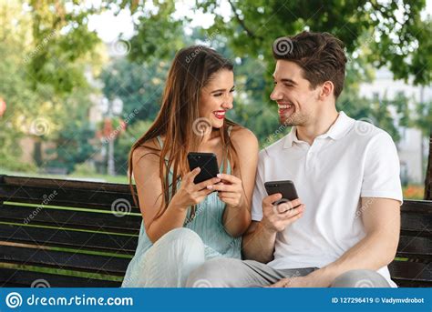 Loving Couple Sitting Outdoors While Using Mobile Phones Stock Image Image Of Heterosexual