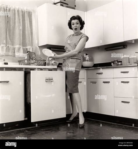 1950s Woman Housewife Wearing Smock Putting Dishes In Automatic Stock