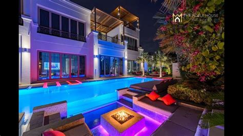 An Outdoor Fire Pit Next To A Swimming Pool At Night With Lights On The