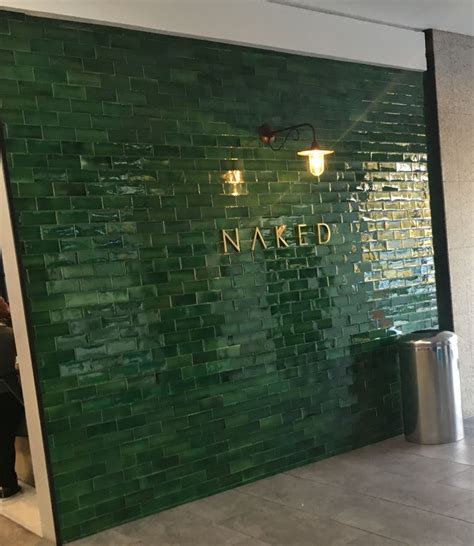 A Green Tiled Wall With The Name Naked Written On It And People Sitting In The Background