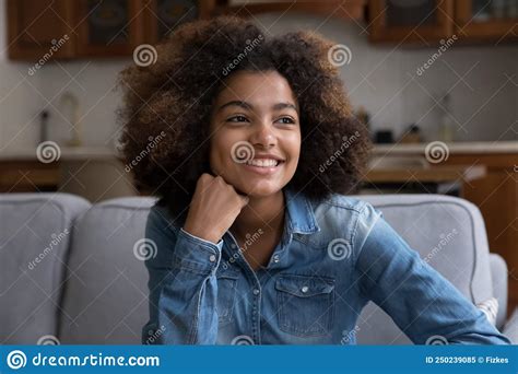 Beautiful African Curly Haired Girl Seated On Couch Staring Aside Stock