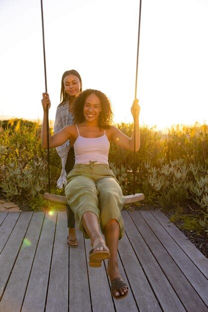 Premium Photo Happy Biracial Lesbian Couple Swinging On Swing In Sunny Garden Lifestyle