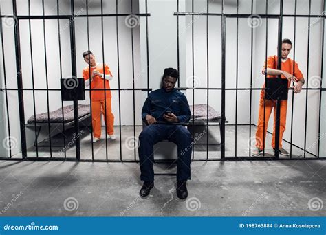 A Strong Black Prison Guard Guards The Cells With Prisoners In The
