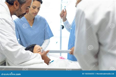 Doctor Adjusting Iv Drip And Oxygen Mask While Patient Lying In Bed