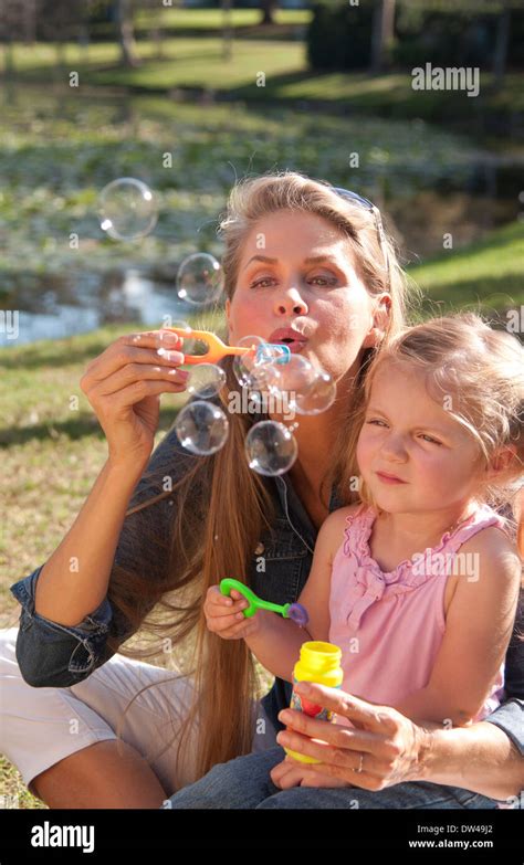 Beautiful Young Mother And Daughter Blowing Bubbles And Snuggling