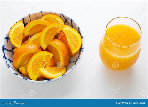 Freshly Squeezed Orange Juice In A Glass Next To A Bowl Of Orange