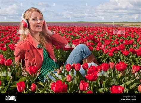 Portrait Of A Beautiful Blond Dutch Girl Listening To Music In Tulips