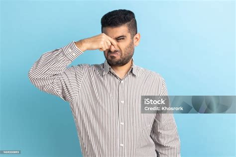 Confused Businessman Standing Pinching His Nose And Looking At Camera
