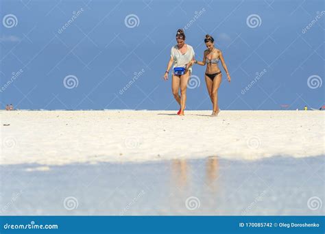 Two Girls In Swimsuits Go To The Ocean On The Tropical Sand Beach Of Zanzibar Island Tanzania