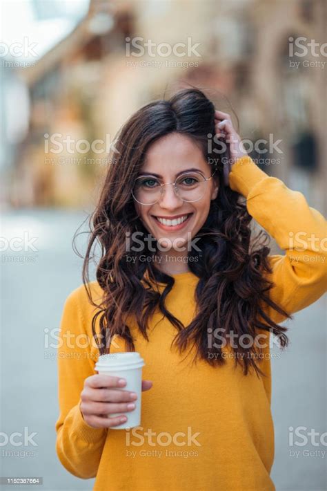 Portrait Of A Happy Young Brunette Woman With Takeout Coffee In Urban