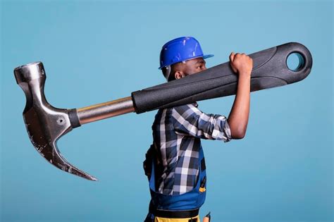 Концепция тяжелой работы афроамериканский строитель с гигантским молотком в студии сильный