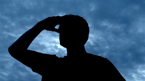 Silhouetted Person In Black Searching Around With Blue Sky In