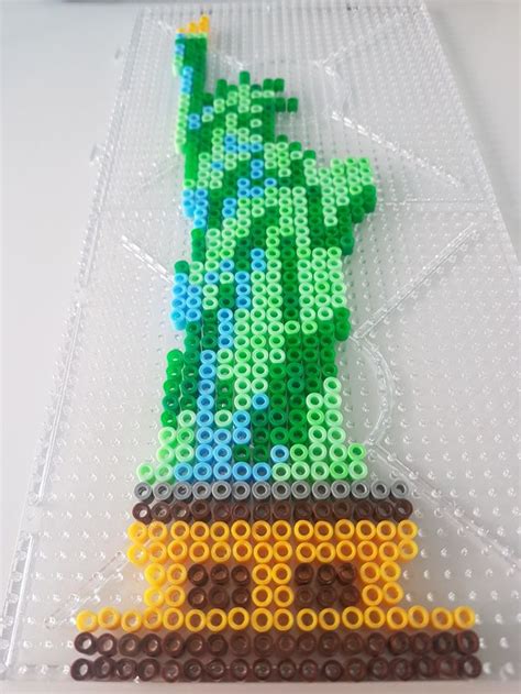 The Statue Of Liberty Made Out Of Legos Is Displayed On A White Table Top