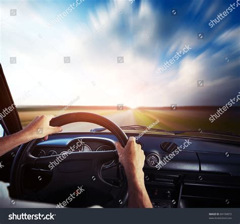 Drivers Hands On A Steering Wheel And Motion Blurred Road And Sky