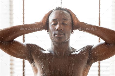 Naked Black Guy Relaxing Taking Shower Standing In Bathroom Indoors