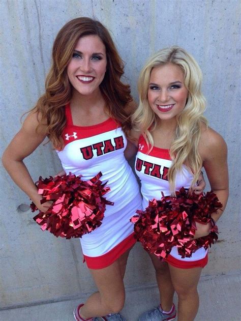 Two Cheerleaders Posing For The Camera With Their Pom Poms