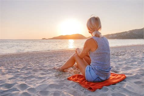Young Woman Sitting On Sand At The Beach At Sunset Stock Image Image