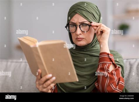 Senior Muslim Lady Squinting Eyes Reading Book Wearing Eyeglasses