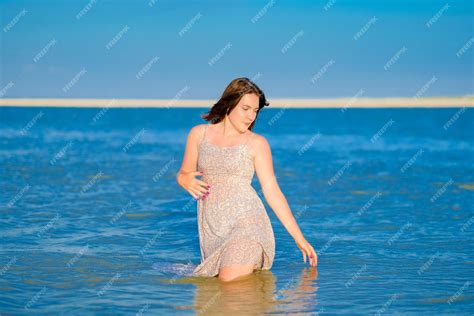 Premium Photo A Young Girl In A Wet Sundress Standing Kneedeep In Sea