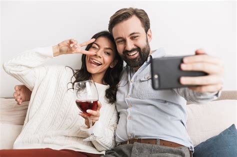Premium Photo Positive Couple Man And Woman Taking Selfie Photo Together On Sofa While