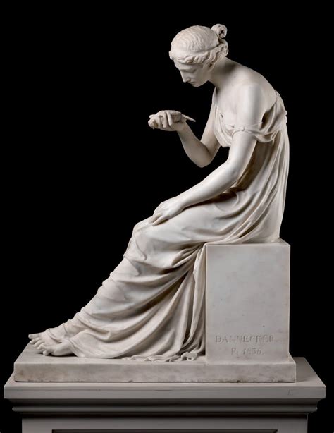 A Statue Of A Woman Sitting On Top Of A White Pedestal With Her Hands