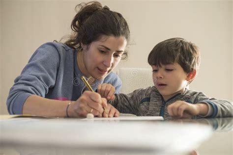 Madre Ayudando A Su Hijo A Hacer Los Deberes Imagen De Archivo Imagen