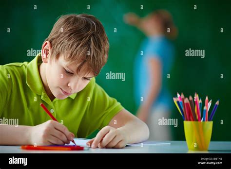Portrait Of Cute Schoolboy Drawing With Colorful Pencils Stock Photo