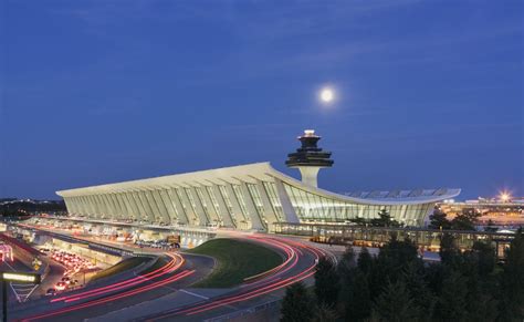 An Airport Terminal At Night With The Moon In The Sky And Cars On The Road