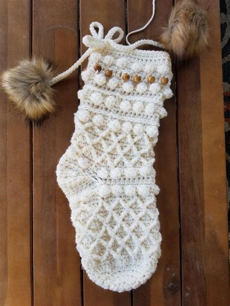 A White Crocheted Stocking With Pom Poms Hanging From It