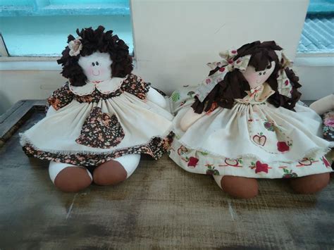 Two Dolls Sitting Next To Each Other On A Table